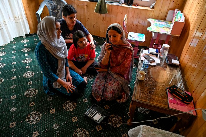 A family in Srinagar speaks on a landline on 17 August, after some phone connectivity was restored in pockets of Kashmir. Mobile and internet services in the region remain suspended.