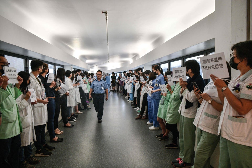 Medical staff hold posters as they form a human chain to express solidarity with anti-extradition bill...