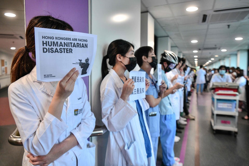 Medical staff hold posters as they form a human chain to express solidarity with anti-extradition bill...
