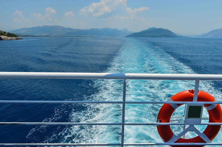 Rear view of Ionian sea against sky and islands from the balcony of a ferryboat .Red lifesaver on the deck of a ferry. Summer vacation in Greece .