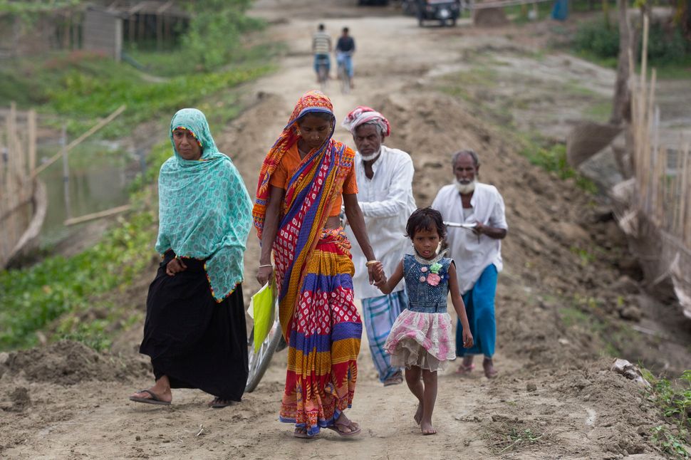 Villagers walk towards a National Register of Citizens (NRC) center to check their names on the final list in Pabhokati village in Morigaon district, in the northeastern Indian state of Assam, Saturday, Aug. 31, 2019. India has published the final citizenship list in the Indian state of Assam, excluding nearly two million people amid fears they could be rendered stateless. The list, known as the National Register of Citizens (NRC), intends to identify legal residents and weed out illegal immigrants from the state. (AP Photo/Anupam Nath)