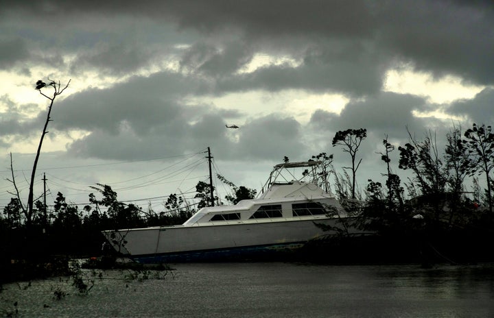 A United States Coast Guard helicopter flies over the areas affected by Hurricane Dorian, as a catamaran thrown onshore by the hurricane lays stranded on a submerged highway near Freeport, Grand Bahama, Bahamas, Tuesday Sept. 3, 2019. Relief officials reported scenes of utter ruin in parts of the Bahamas and rushed to deal with an unfolding humanitarian crisis in the wake of Hurricane Dorian, the most powerful storm on record ever to hit the islands. (AP Photo/Ramon Espinosa)