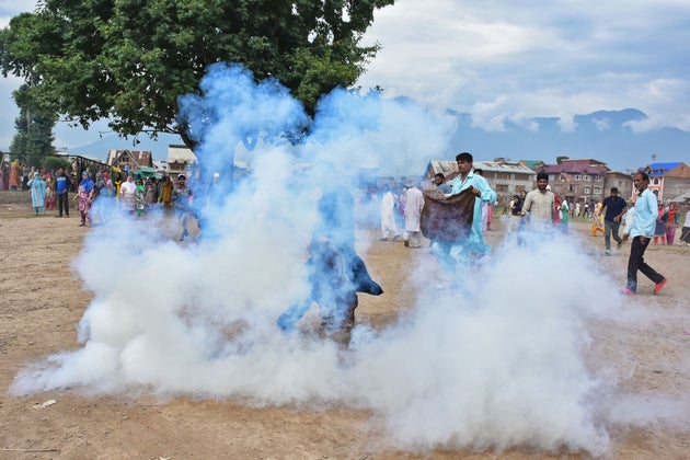 Kashmiri men try to block the teargas smoke during clashes between Indian forces and people in Srinagar...