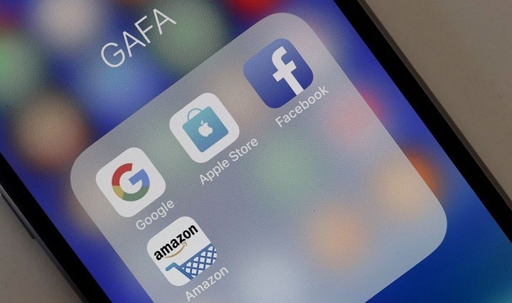 A photo illustration shows logos for Google, Apple, Facebook, and Amazon applications on the screen of an Apple iPhone.