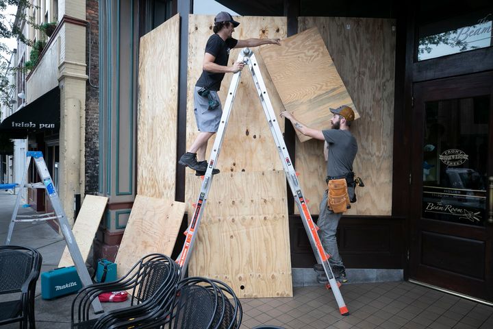 Andrew West, left and Michael Leibler install plywood over the windows of the Front Street Brewery ahead of Hurricane Dorian on Wednesday, Sept. 4, 2019 in Wilmington, N.C. The popular downtown restaurant will remain open once the windows have been covered. (Robert Willett/The News & Observer via AP)