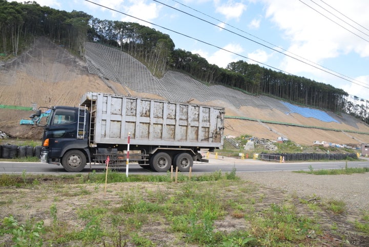 時おり通る工事用のトラック。平日になると大型車の交通量はかなり増えるという＝2019年9月1日