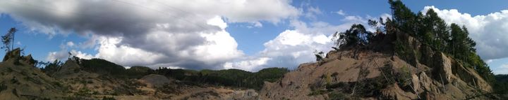 パノラマ機能で山が350m移動した現場を撮影した。右に見える山が、左から剥がれて一気にずれたという＝2019年9月1日