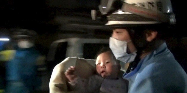 An eight-month-old baby is carried away by a rescue worker after being rescued from her collapsed home...