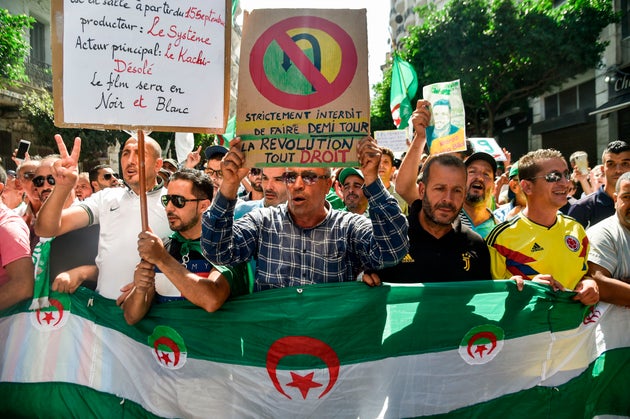 Protesters march with Algerian national flags and anti-establishment signs during a demonstration against...