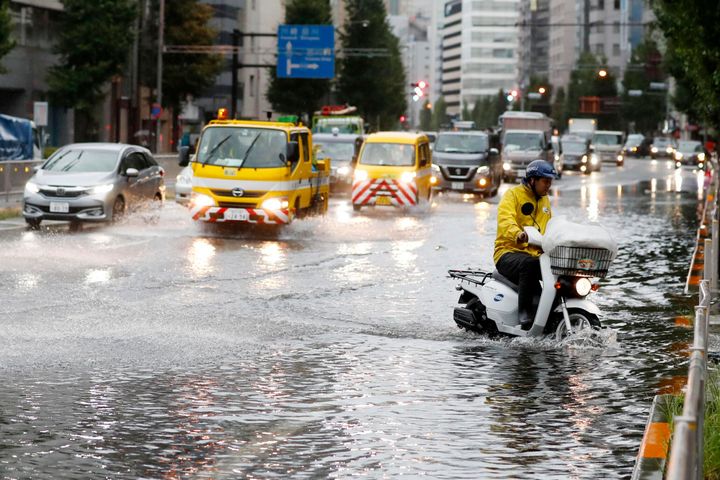 A man rides a moped through a flooded street due to a typhoon in Tokyo Monday September 9, 2019. (Kyodo News via AP)