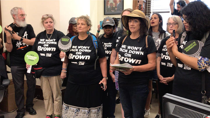 Protesters crashed Sen. Chris Coons' office to urge the Delaware Democrat to stop supporting judicial nominees who won't say if they think Brown v. Board of Education was correctly decided.