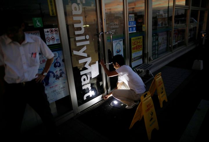 A man uses a flashlight as he locks up his shop during a blackout caused by Typhoon Faxai in Kisarazu, Chiba prefecture, Japan September 9, 2019. REUTERS/Issei Kato