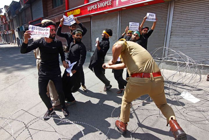 A police officer beats Kashmiri shiite muslims as they tried to took out a Muharram procession in Srinagar, Kashmir on September 8, 2019.