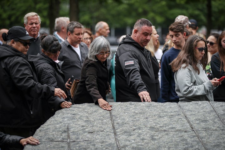 NEW YORK, NY - MAY 30: Attendees touch one of the stone monoliths following the dedication ceremony for the new 9/11 Memorial