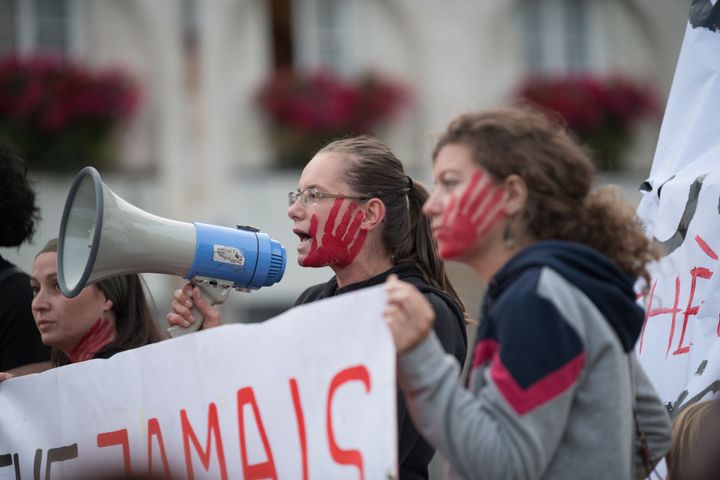 Women with red hands painted on their faces participate in a night march in Nantes, France, to protest the killing of women by their spouses or former companions.