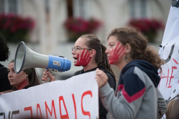 Women with red hands painted on their faces participate in a night march in Nantes, France, against the killing of women by t