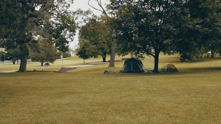 People sleep in tents in Victoria Park, a grassy square city block with mature trees across the street from St. John’s Anglican Church.