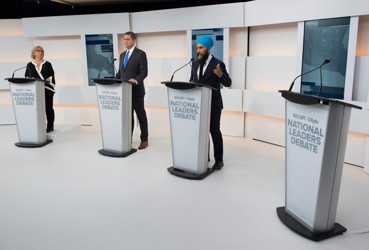 A empty podium is pictured as Green Party Leader Elizabeth May, left, Conservative Leader Andrew Scheer, centre, and NDP Leader Jagmeet Singh take part during the Maclean's/Citytv debate.