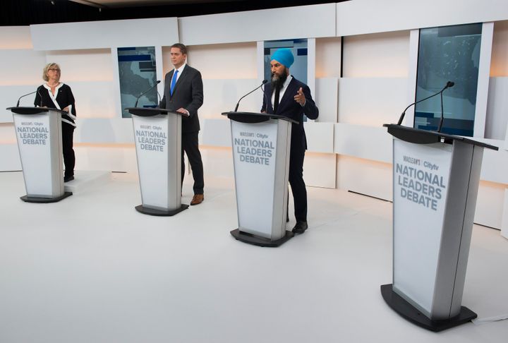 A empty podium is pictured as Green Party Leader Elizabeth May, left, Conservative Leader Andrew Scheer, centre, and NDP Leader Jagmeet Singh take part during the Maclean's/Citytv debate.