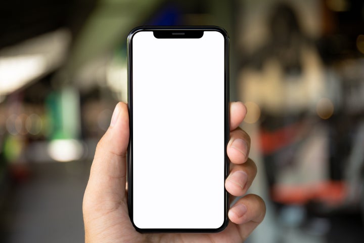 man hand holding phone with isolated screen on the background of a city street（イメージ写真）