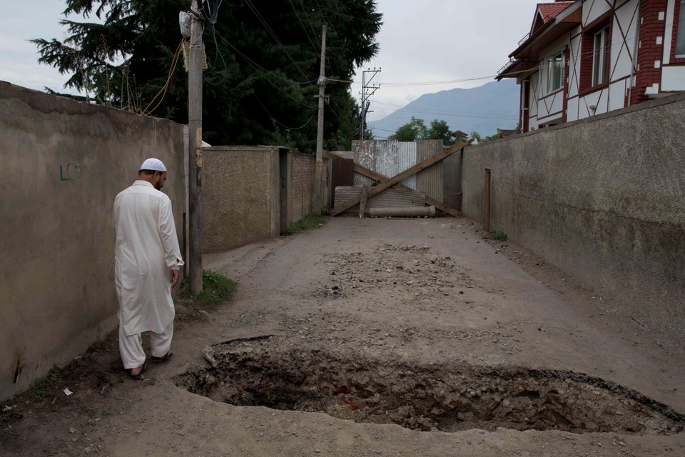 A Kashmiri man walks past a crater dug up by locals to prevent police vehicles enter the area amid curfew-like...