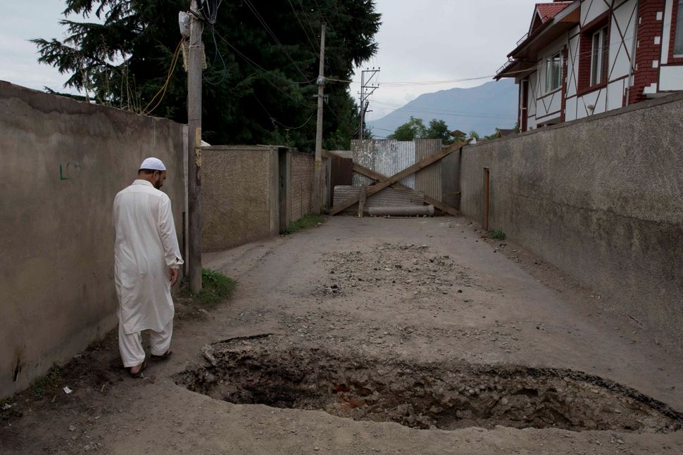 A Kashmiri man walks past a crater dug up by locals to prevent police vehicles enter the area amid curfew-like restrictions in Srinagar, Aug. 16, 2019. 