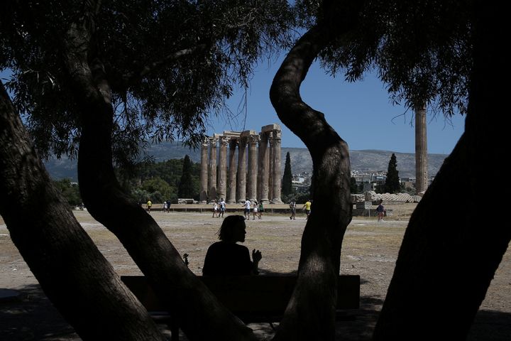 A tourist sits under the shadow of a tree during a hot day, at the archaeological site of the Temple of Zeus in Athens, Greece July 4, 2019.REUTERS/Costas Baltas