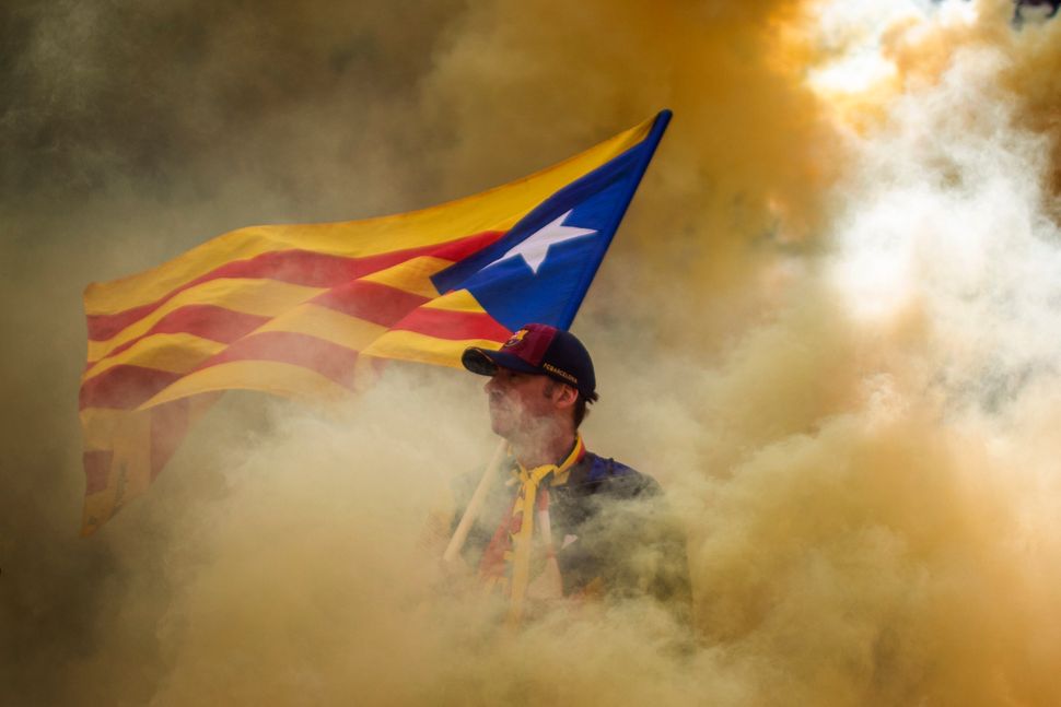 Ένας άνδρας που κρατά μια σημαία ανεξαρτησίας φαίνεται μέσα από το καπνό ενός καπνογόνου, που έριξαν οι διαδηλωτές, κατά τη διάρκεια της Εθνικής Ημέρας της Καταλονίας, στη Βαρκελώνη της Ισπανίας, στις 11 Σεπτεμβρίου.