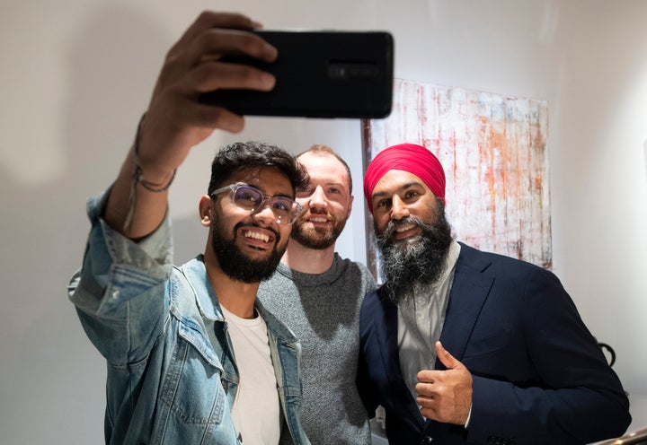 NDP Leader Jagmeet Singh takes a photo with people at a coffee shop following a campaign announcement in Toronto on Friday.