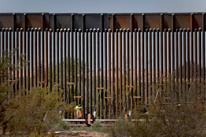 A government contractor walks beside a completed section of Pentagon-funded border wall along the Colorado River this month i