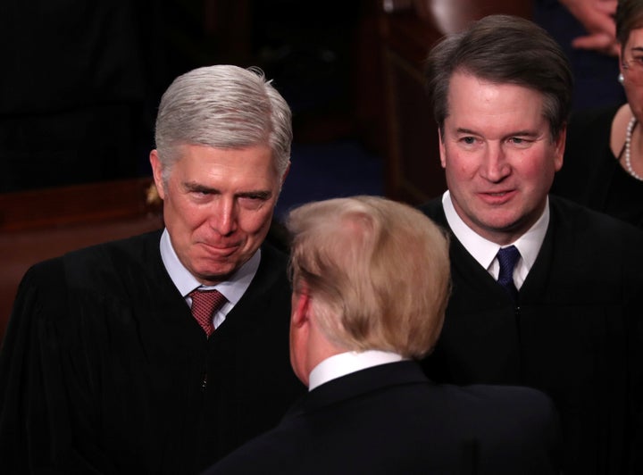 President Donald Trump talks with Supreme Court Justice Neil Gorsuch (L) and Justice Brett Kavanaugh on Capitol Hill in February.