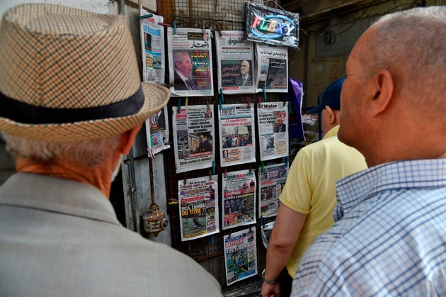 People view the covers of national and foreign newspapers, with the announced Algerian presidential election...