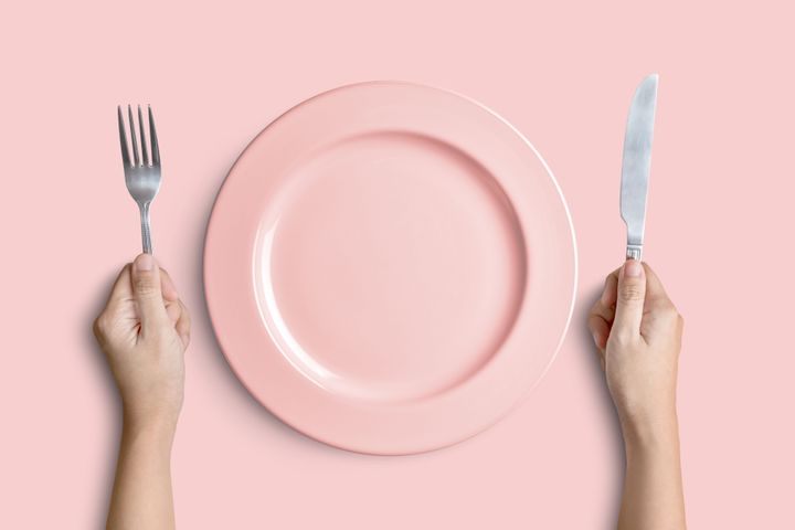 Dinner place setting. A pink plate with silver fork and knife isolated on pink background with clipping path