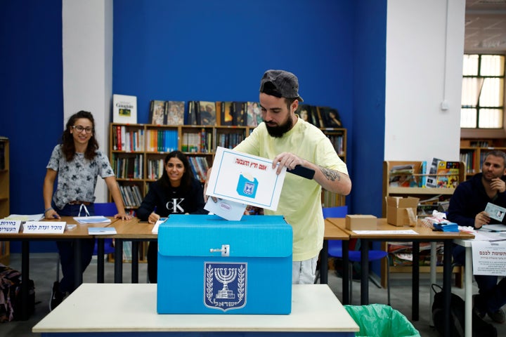 A man casts his vote as he holds up a small placard during Israel's parliamentary election, at a polling station in Tel Aviv,