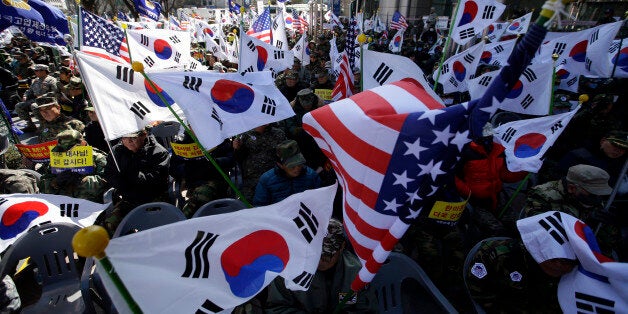 South Korean Vietnam War veterans hold flags from South Korea and the United States during a rally denouncing...