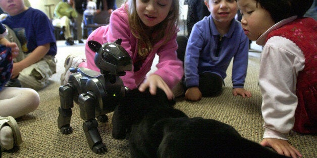 Arianna Stoltz, 5, center, introduces Shanti, a stuffed animal dog, to Aibo, a robotic dog, as Wing-Yee...