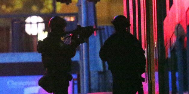 Armed tactical response officers enter the building after shots were fired during a cafe siege in the...