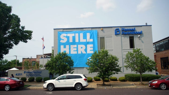 A banner stating "STILL HERE" hangs on the side of the Planned Parenthood Building after a judge granted a temporary restrain