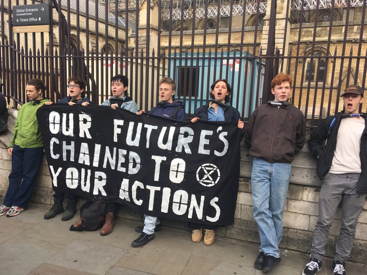 Protesters from the youth wing of Extinction Rebellion tie themselves to a fence outside Parliament