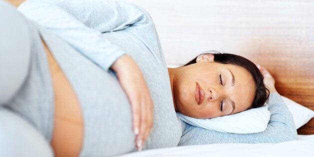 Serene pretty young pregnant woman sleeping on the bed