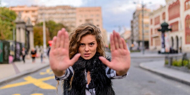 Scared woman raising hand up in defense afraid