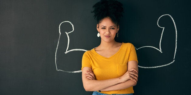 Shot of a woman posing with a chalk illustration of flexing muscles against a dark background