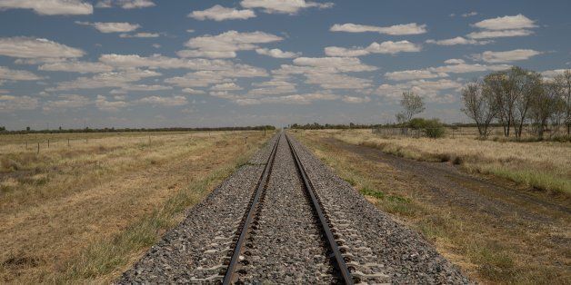 A railway line in the Queensland outback with a blue sky with clouds