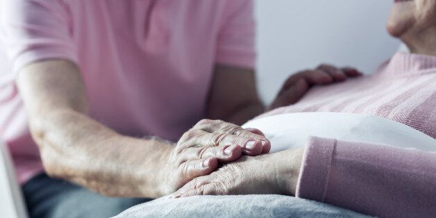 Senior man holding hand of his ill wife, close up