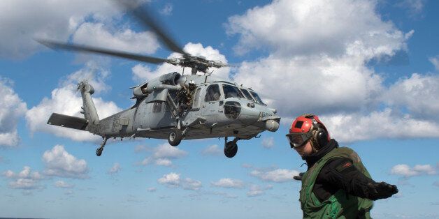 A helicopter landing signal crew member gestures as a helicopter takes off from the deck of the USS George H.W. Bush in the Atlantic ocean on October 26, 2017, as the carrier strike group takes part in Operation Bold Alligator, a multinational warfare exercise hosted by the United States. / AFP PHOTO / Andrew CABALLERO-REYNOLDS (Photo credit should read ANDREW CABALLERO-REYNOLDS/AFP/Getty Images)