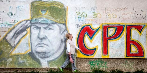 A wiman walks past a graffiti depicting former Bosnian Serb commander Ratko Mladic and reading 'Serbia' written in Cyrillic, painted on a wall in Belgrade on Nocember 22, 2017. Ratko Mladic, who was convicted of genocide on November 22, 2017, believed himself to be a crusading defender of the Serbs but was dubbed the 'Butcher of Bosnia' for mass slaughter at the hands of his forces. / AFP PHOTO / OLIVER BUNIC (Photo credit should read OLIVER BUNIC/AFP/Getty Images)