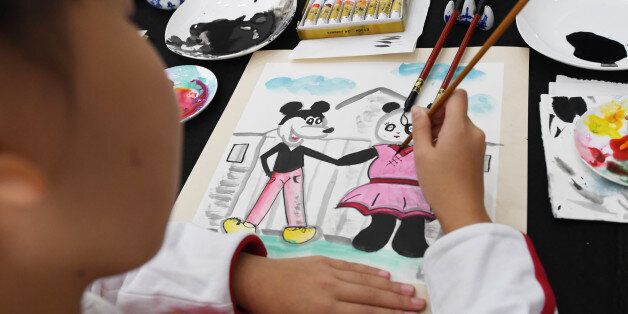 A student paints Mickey Mouse and panda figures in a calligraphy class during a visit by US First Lady Melania Trump and China's First Lady Peng Liyuan at Banchang Primary School in Beijing on November 9, 2017. Donald Trump and Xi Jinping put their professed friendship to the test on November 9 as the least popular US president in decades and the newly empowered Chinese leader met for tough talks on trade and North Korea. / AFP PHOTO / POOL / GREG BAKER (Photo credit should read GREG BAKE