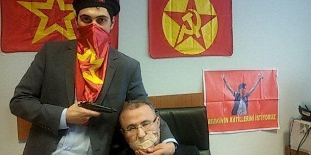 A gunman poses with Prosecutor Mehmet Selim Kiraz with a gun on his head after being taken hostage in his office in a court house in Istanbul March 31, 2015. A far-left Turkish group took the Istanbul prosecutor hostage on Tuesday and threatened to kill him, prompting special forces officers to enter the courthouse and police to evacuate the building. The Revolutionary People's Liberation Party-Front (DHKP-C) published a picture of the prosecutor with the gun to his head and said it would kill h