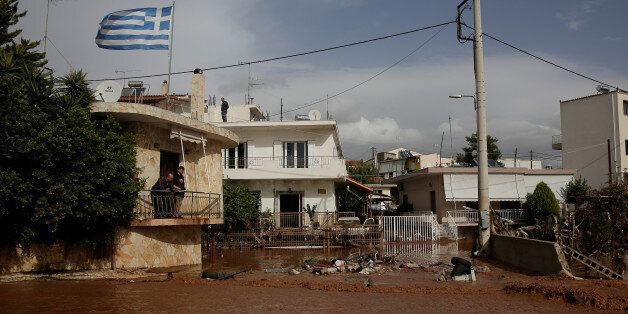 A Greek national flag flutters atop a terrace as locals observe a flooded street following a heavy rainfall in the town of Mandra, Greece, November 15, 2017. REUTERS/Alkis Konstantinidis