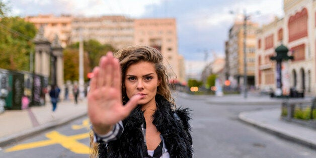 Scared woman raising hand up in defense afraid